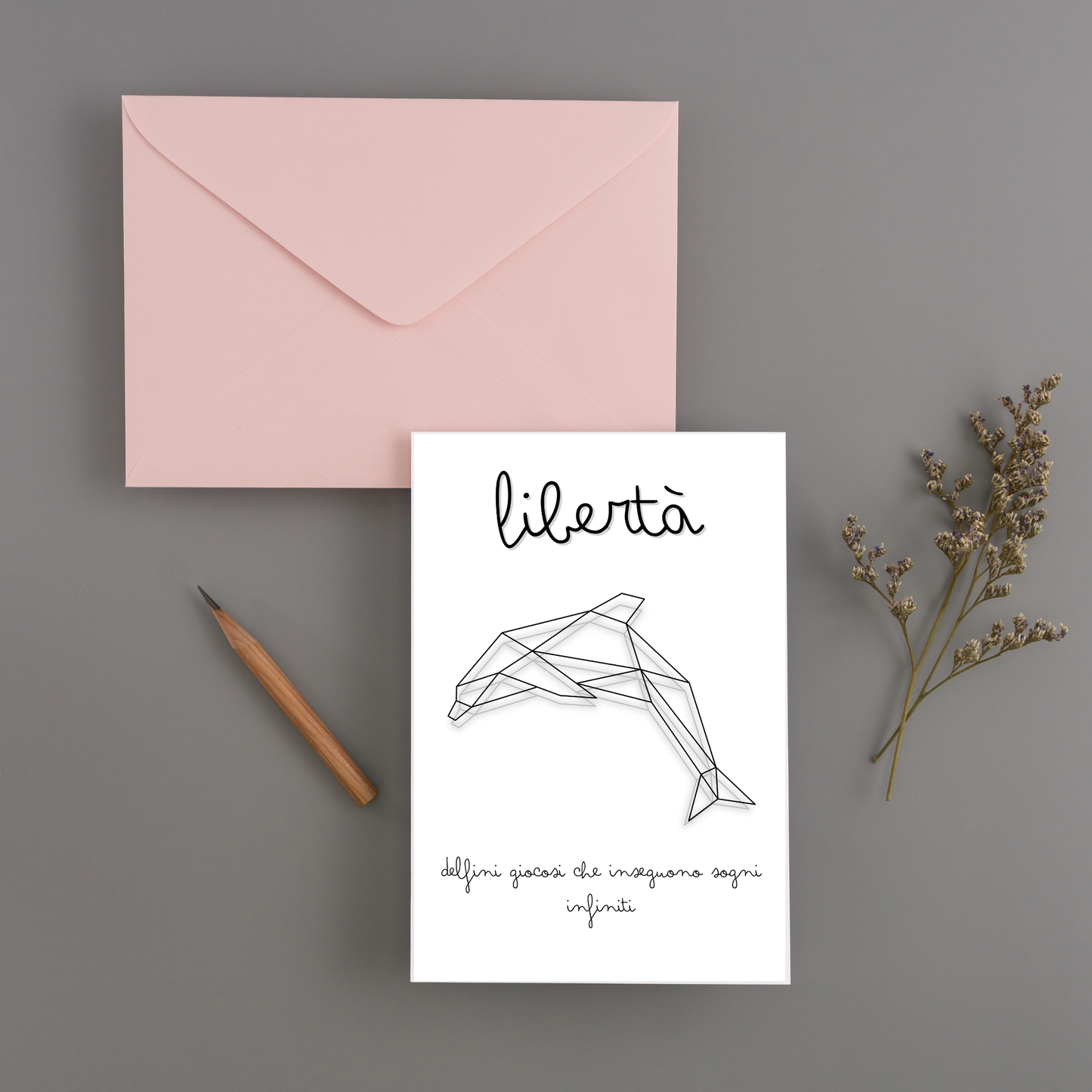 Stampa ORIGAMI INSPIRE Dolphin stampata a cartolina di invito, fotografata su piano con busta rosa.