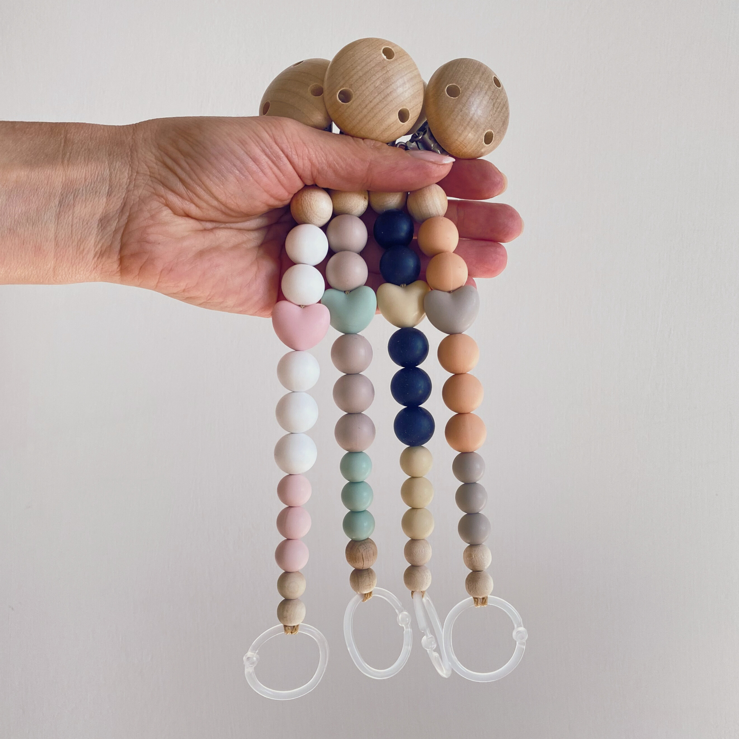 Catenelle portaciuccio in silicone e legno con perla centrale a forma di cuore nelle 4 varianti di colore.