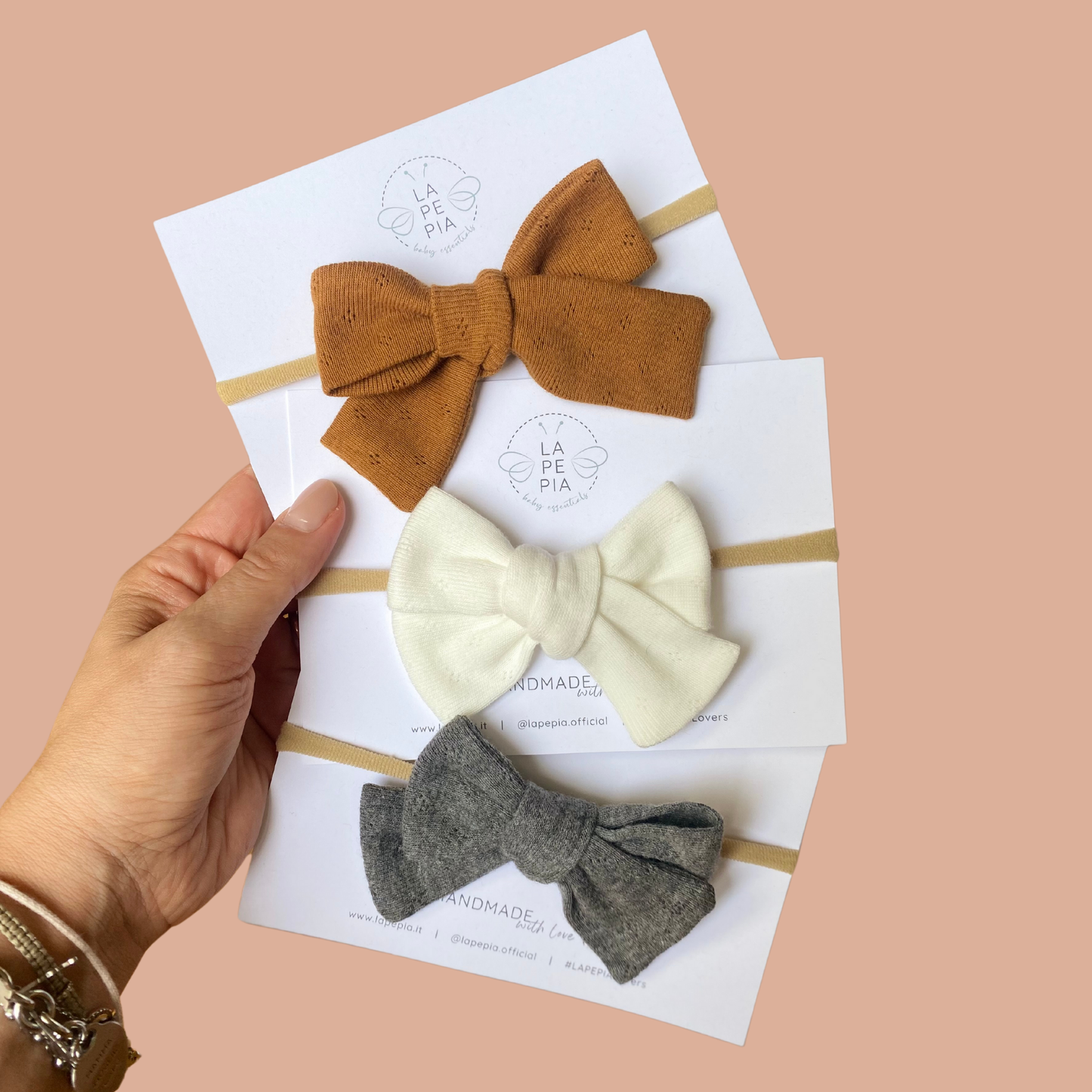 Fiocco in jersey di cotone annodato su fascia in nylon nei colori Caramel, Snowbound e London Fog.