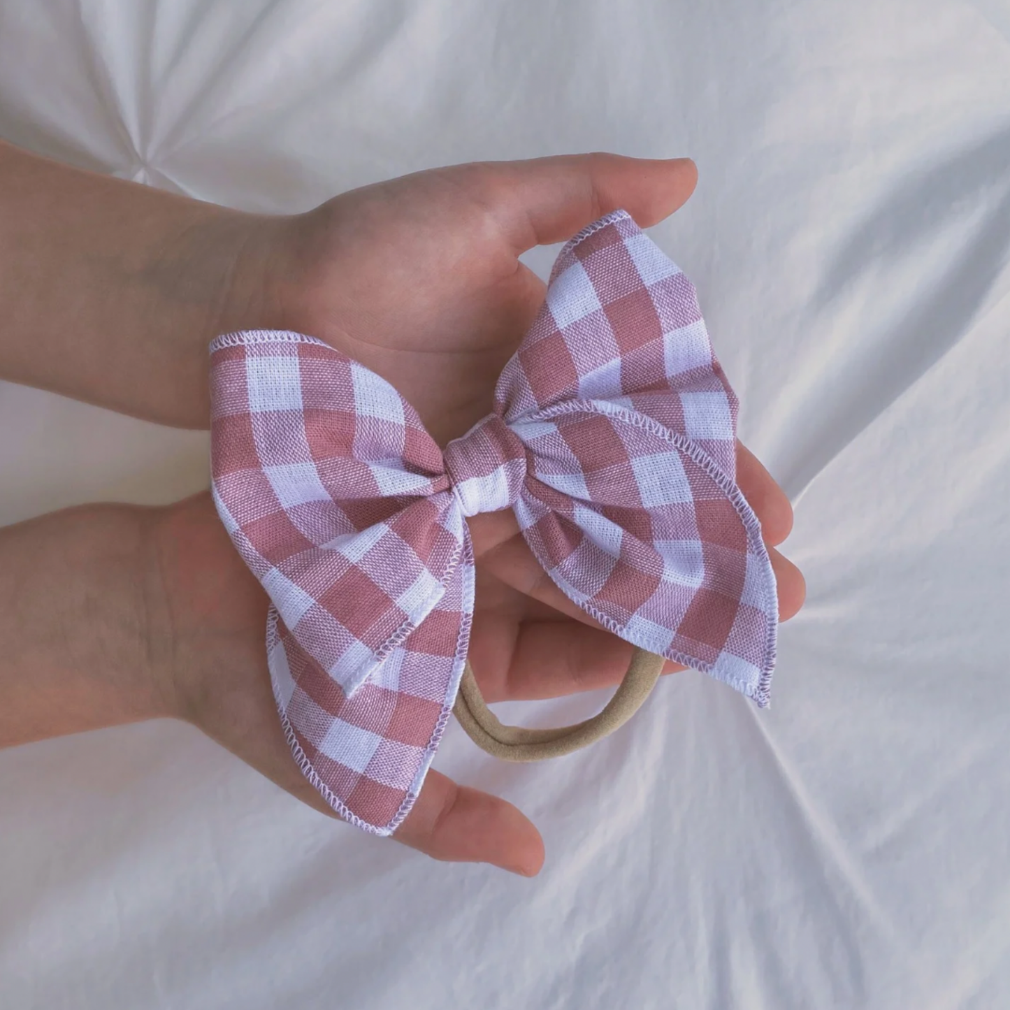 Fiocco per capelli rosa antico tra le mani di una bambina