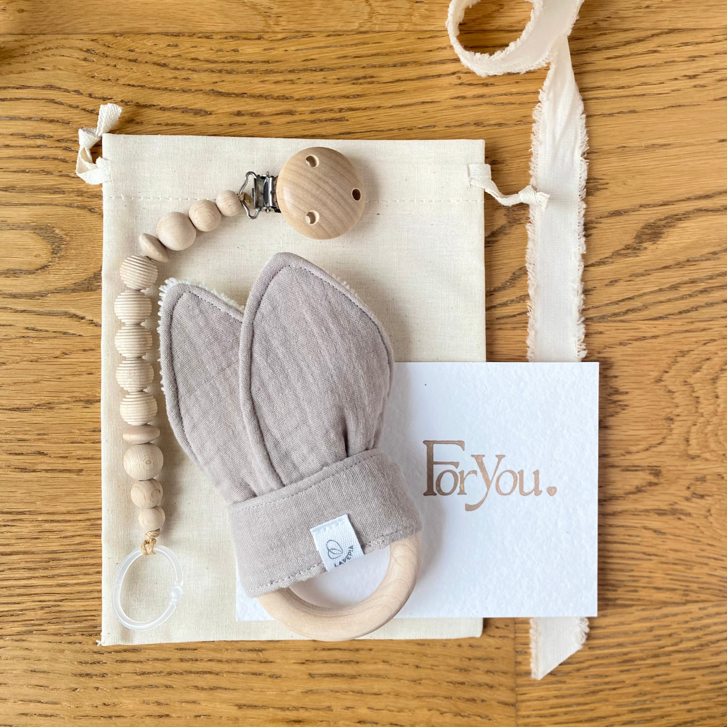 Set regalo Little Wonder Box 'Little Treasures' nella variante Beige, con catenella portaciuccio honey maple, dou dou beige con anello dentizione e sacchettino protettivo in cotone. LAPEPIA.