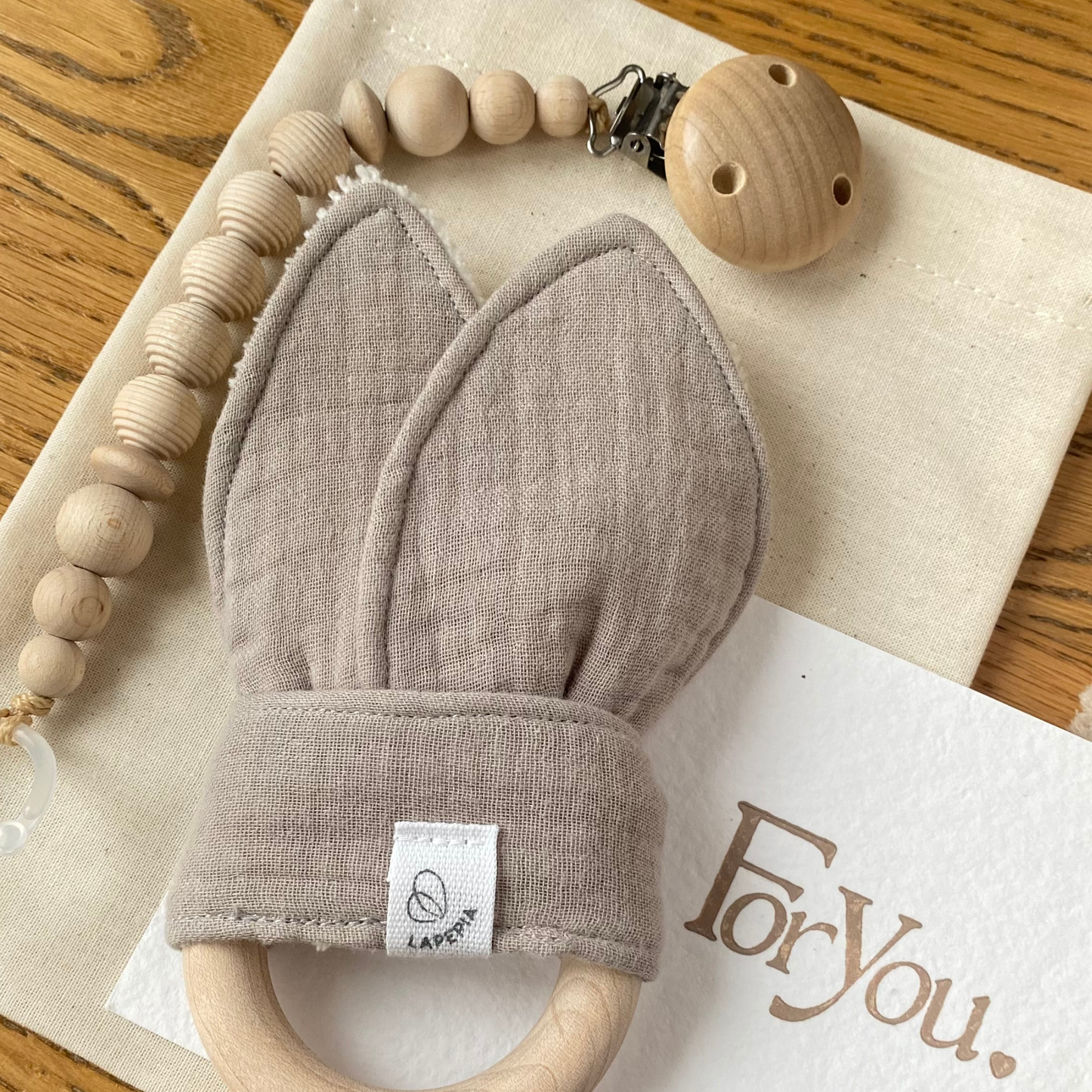 Set regalo Little Wonder Box 'Little Treasures' nella variante Beige, con catenella portaciuccio honey maple, dou dou beige con anello dentizione e sacchettino protettivo in cotone. LAPEPIA.