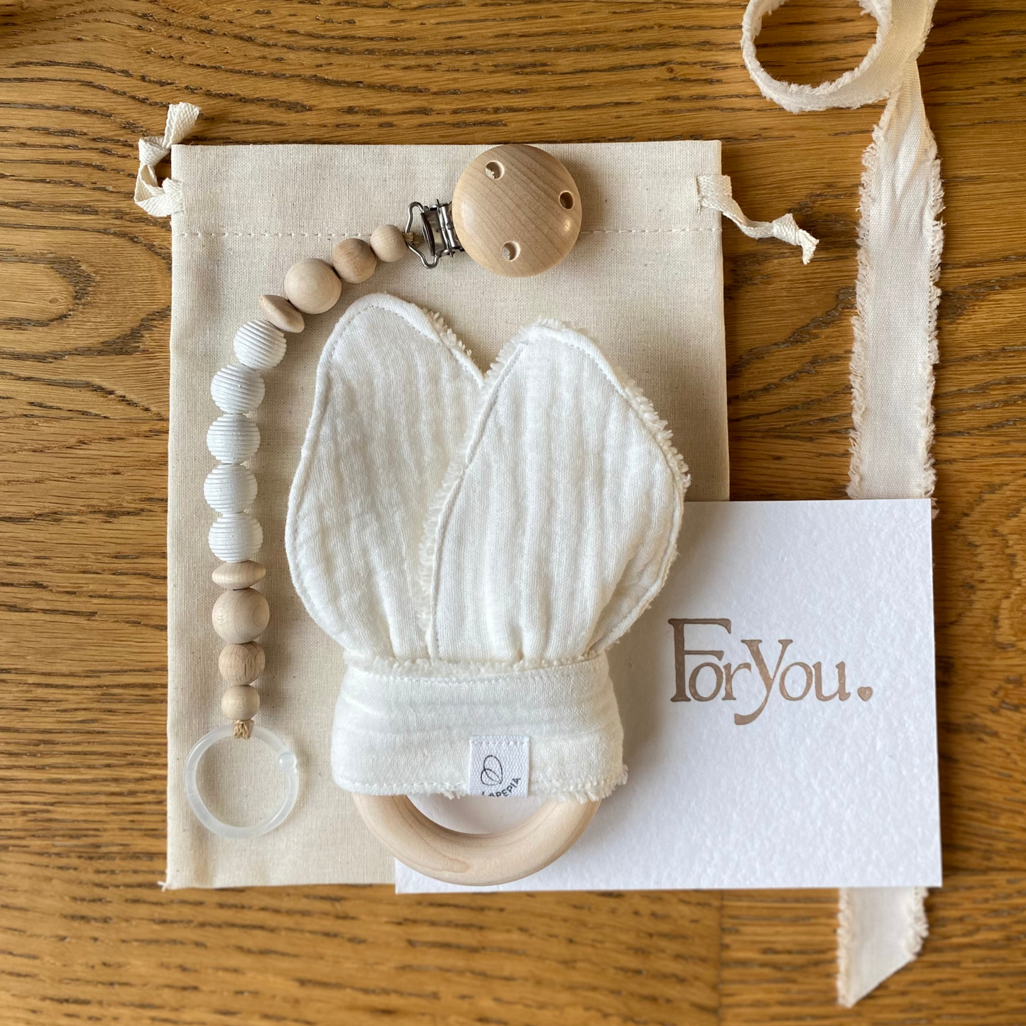 Set regalo Little Wonder Box 'Little Treasures' nella variante Cream, con catenella portaciuccio snowbound, dou dou cream con anello dentizione e sacchettino protettivo in cotone. LAPEPIA.