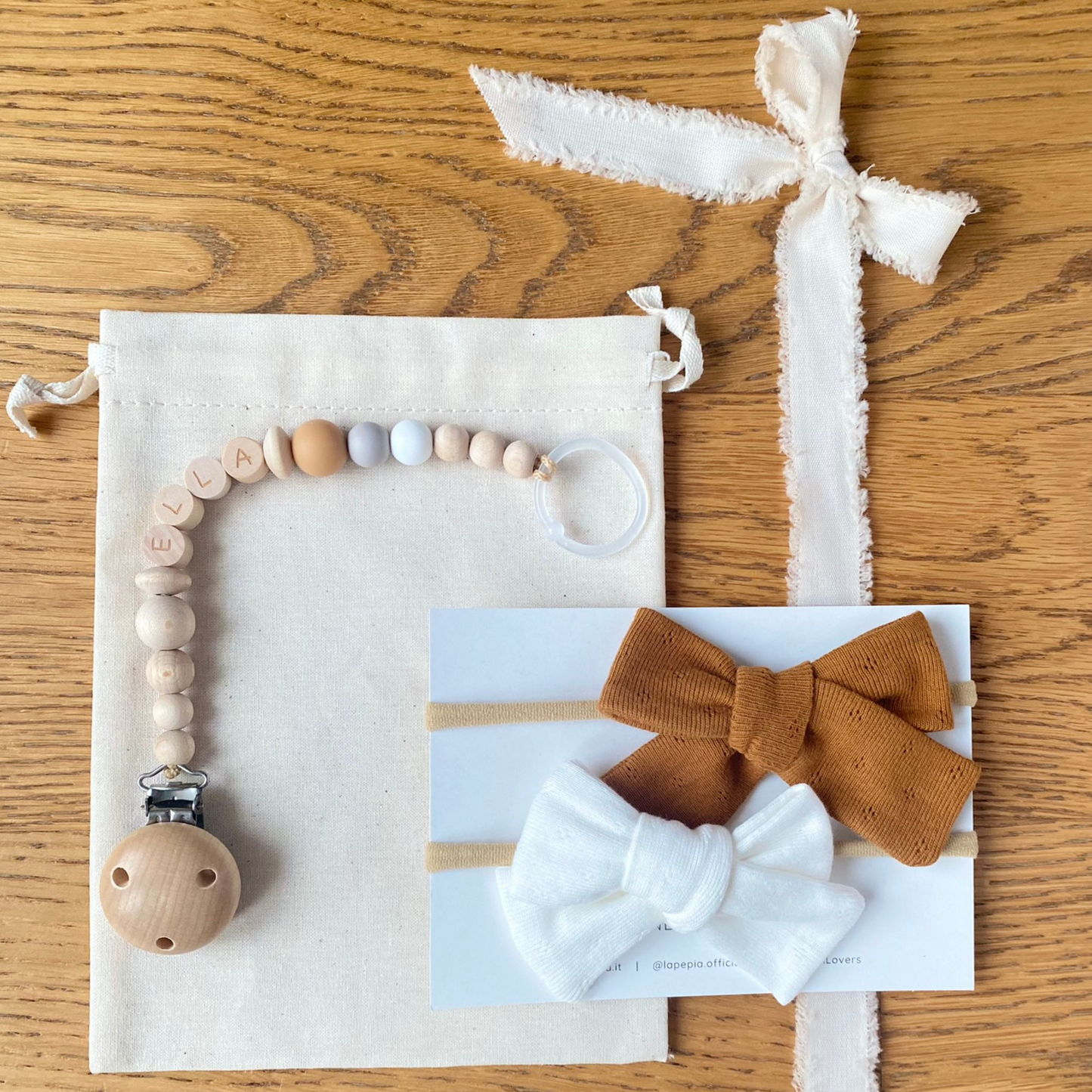 Set regalo Little Wonder Box 'NameIT & LoveIT' nella variante colore Urban Caramel, composto da 2 fiocchi per capelli, catenella portaciuccio personalizzabile con nome e sacchettino protettivo in cotone. LAPEPIA.