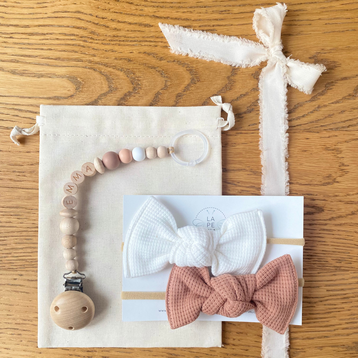 Set regalo Little Wonder Box 'NameIT & LoveIT' nella variante colore Peachy Sunset, composto da 2 fiocchi per capelli, catenella portaciuccio personalizzabile con nome e sacchettino protettivo in cotone. LAPEPIA.