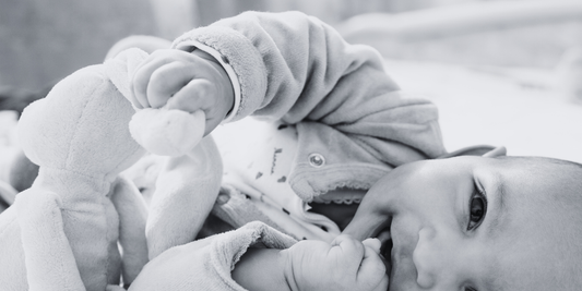 Neonato che stringe il suo doudou vicino al viso