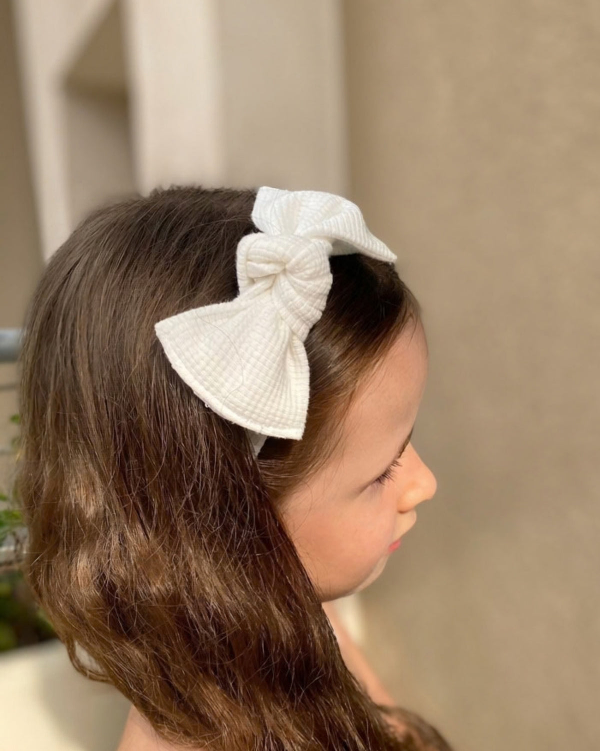 Bimba con fascia per capelli in jersey di cotone nido d'ape colore bianco con fiocco morbido