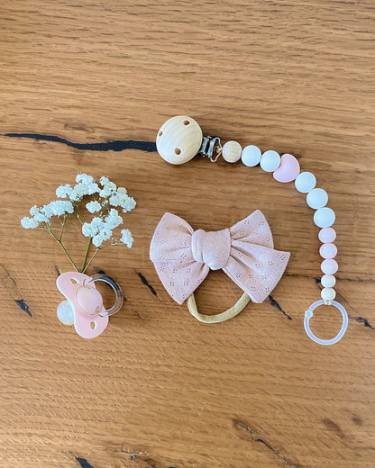 Set regalo con catenella portaciuccio in silicone rosa e legno, fiocco per capelli in cotone.