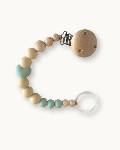 Catenella portaciuccio in silicone e legno nei toni menta e beige con elemento a forma di cuore e clip in legno.