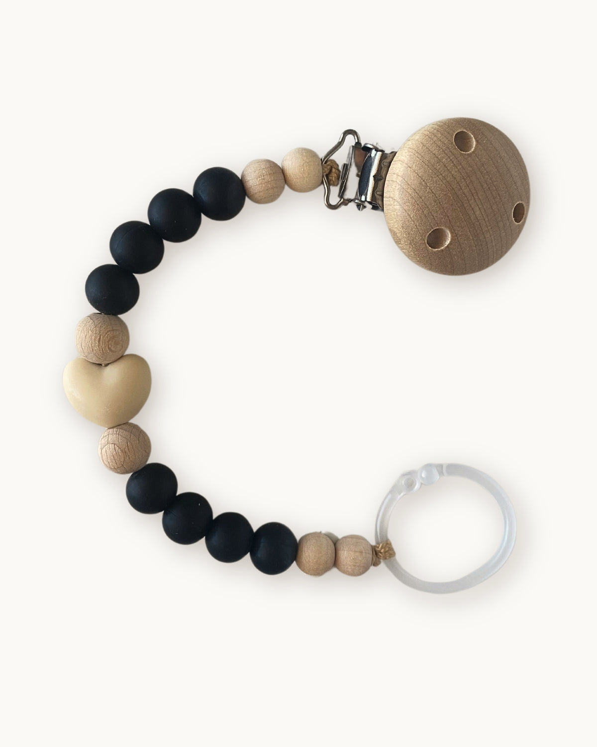 Catenella portaciuccio in silicone alimentare nero con dettaglio cuore beige e clip in legno naturale.
