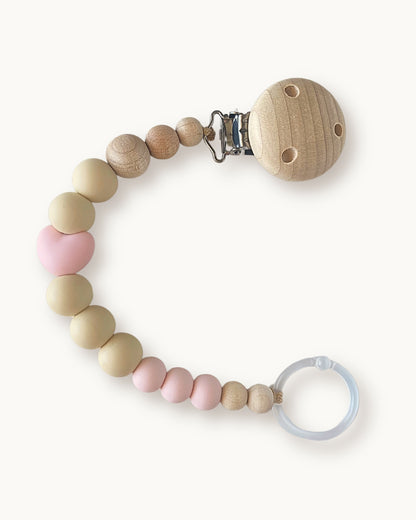Catenella portaciuccio in silicone rosa cipria e beige con dettaglio a cuore e clip in legno per neonata.