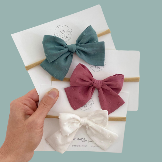 Collezione di fiocchi per capelli Classic Bow Plumetis in tre colori: vintage mauve, soft white e antique green. Eleganti accessori per capelli da neonata e bambina.