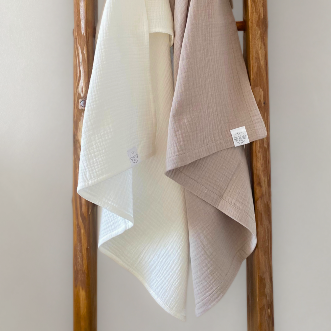 Copertine in mussola di cotone nei colori beige e cream annodate su una scala vintage.