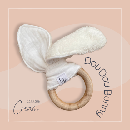 Doudou a forma di orecchie di coniglio in mussola e spugna di bamboo, con anello dentizione in legno colore cream.