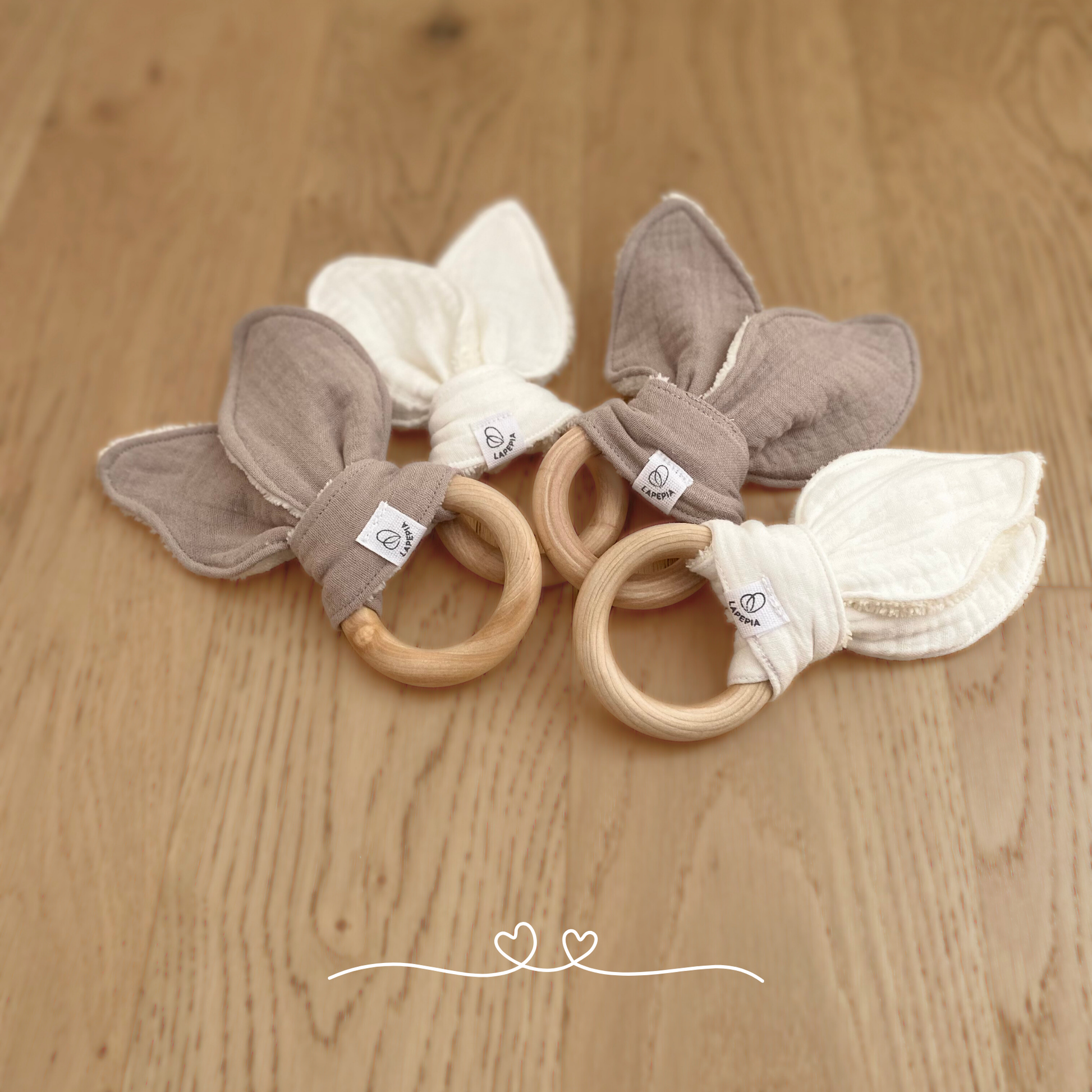 Doudou a forma di orecchie di coniglio in mussola e spugna di bamboo, con anello dentizione in legno nei colori cream e beige