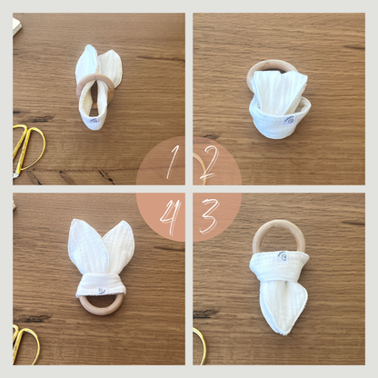 Doudou a forma di orecchie di coniglio in mussola e spugna di bamboo, con anello dentizione. Istruzioni in 4 fasi su come si annoda il tessuto sull'anello in legno.