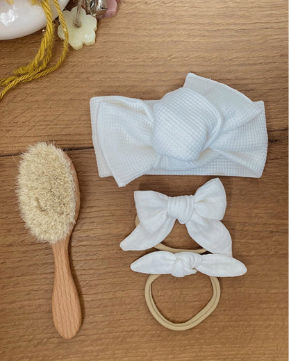 Flatlay con fascia per capelli nido d'ape colore panna, elastico e spazzola per neonato in legno