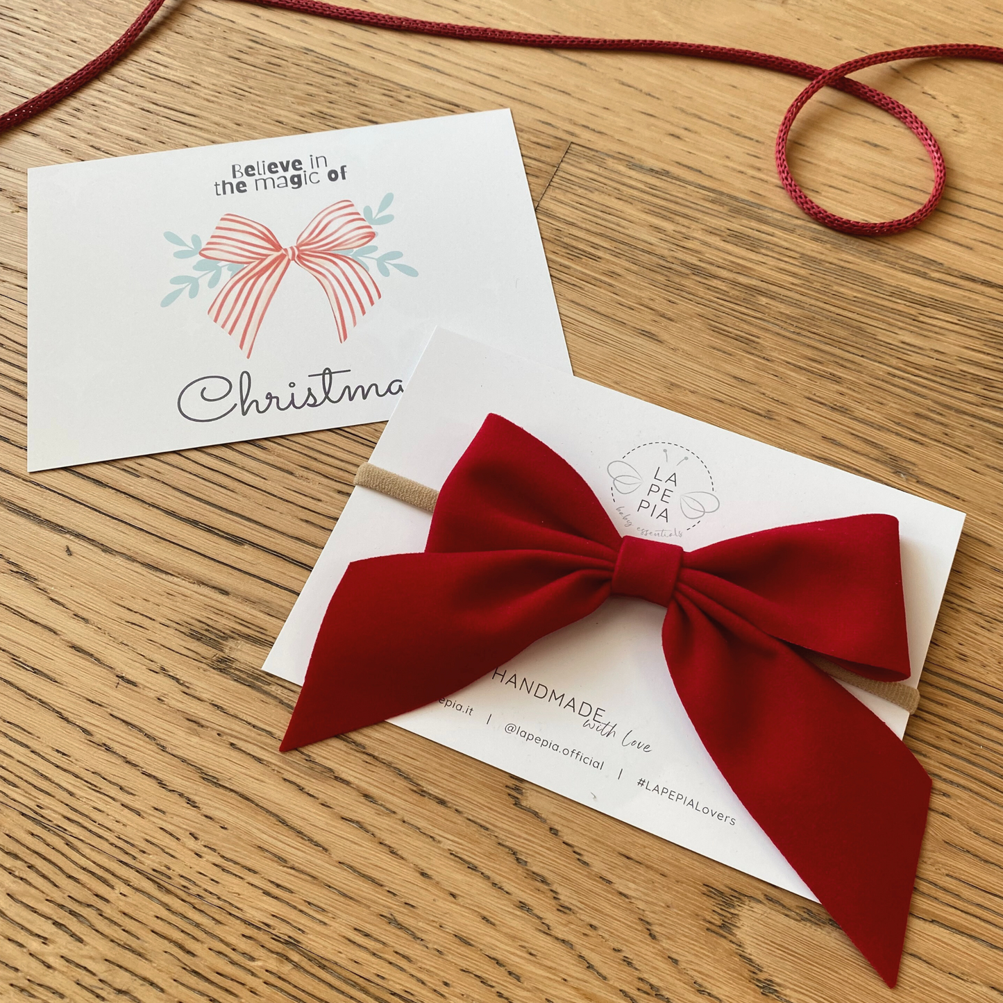 Fiocco per capelli confezionato su cartolina con grafica "Believe in the magic of Christmas"