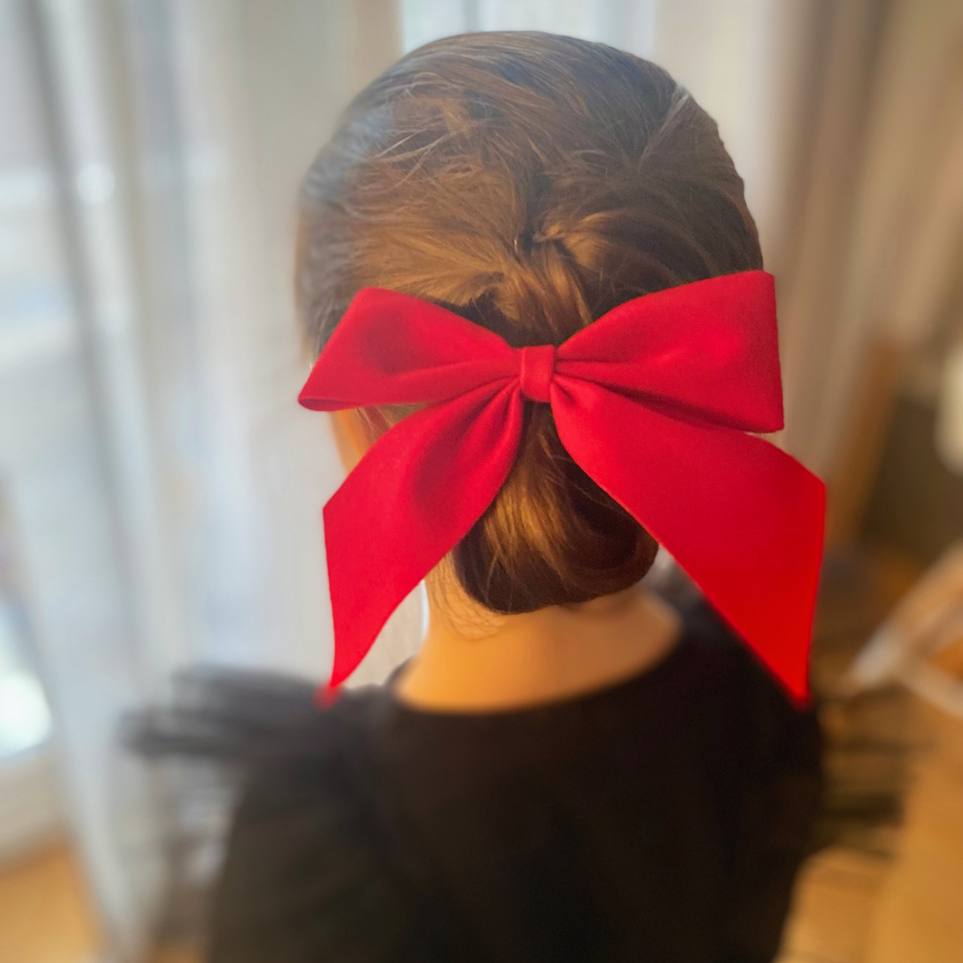 Fiocco in velluto rosso "JingleBOW" indossato su acconciatura bambina con chignon laterale.