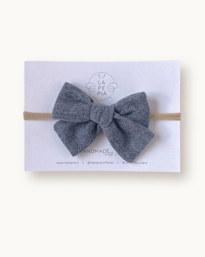 Fiocco per capelli Classic Bow color grigio in cotone lavorato, fatto a mano su fascia morbida per neonata.