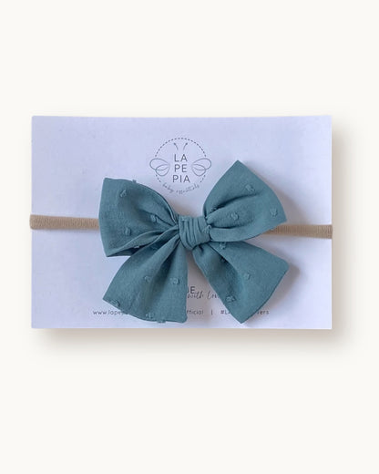 Fiocco per capelli da bambina e neonata Classic Bow in cotone plumetis antique green fatto a mano su fascia morbida in nylon.