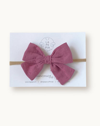 Fiocco per capelli Classic Bow in cotone plumetis colore vintage mauve su fascia elasticizzata per neonata e bambina.