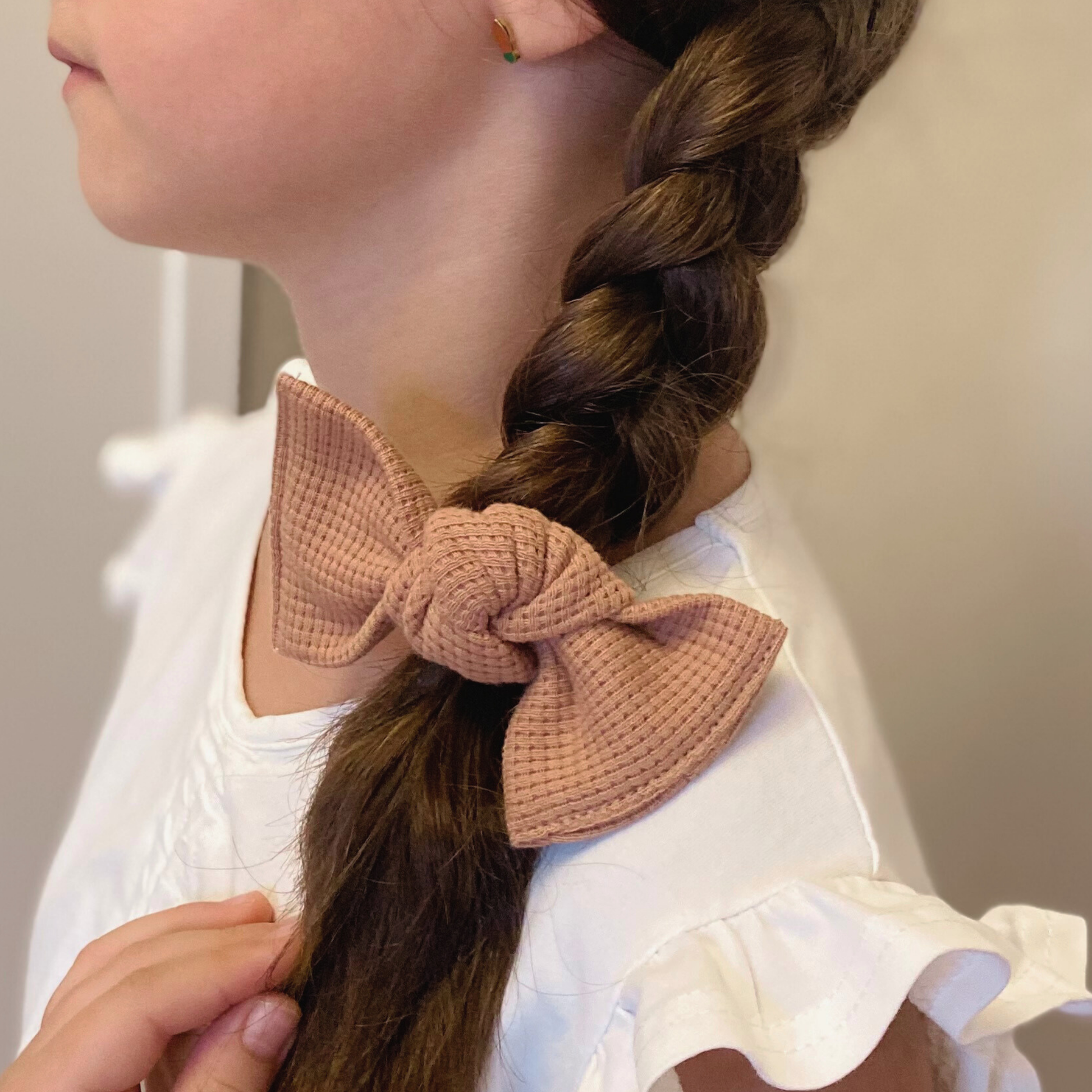Fiocco per capelli in jersey di cotone nel colore peachy sunset, indossato.