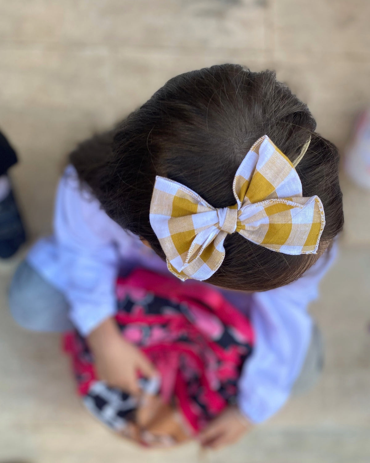Bambina vista dall'alto con fiocco per capelli a quadretti vichy giallo e bianco della linea Sugarpop.