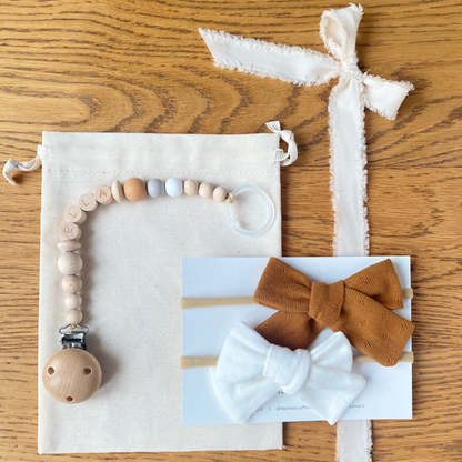 Set regalo Little Wonder Box 'NameIT & LoveIT' nella variante colore Urban Caramel, composto da 2 fiocchi per capelli, catenella portaciuccio personalizzabile con nome e  sacchettino protettivo in cotone. LAPEPIA.