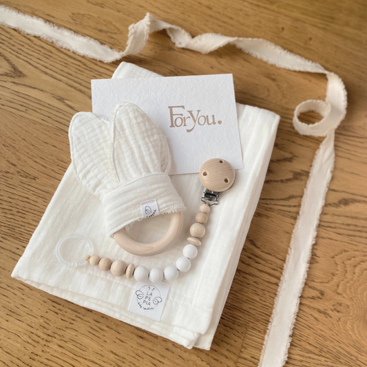 Set regalo Little Wonder Box 'NewBorn Essentials' nella variante Cream composto da copertina in mussola cream, Dou Dou cream con anello dentizione, catenella portaciuccio snowbound e sacchettino protettivo in cotone. LAPEPIA.
