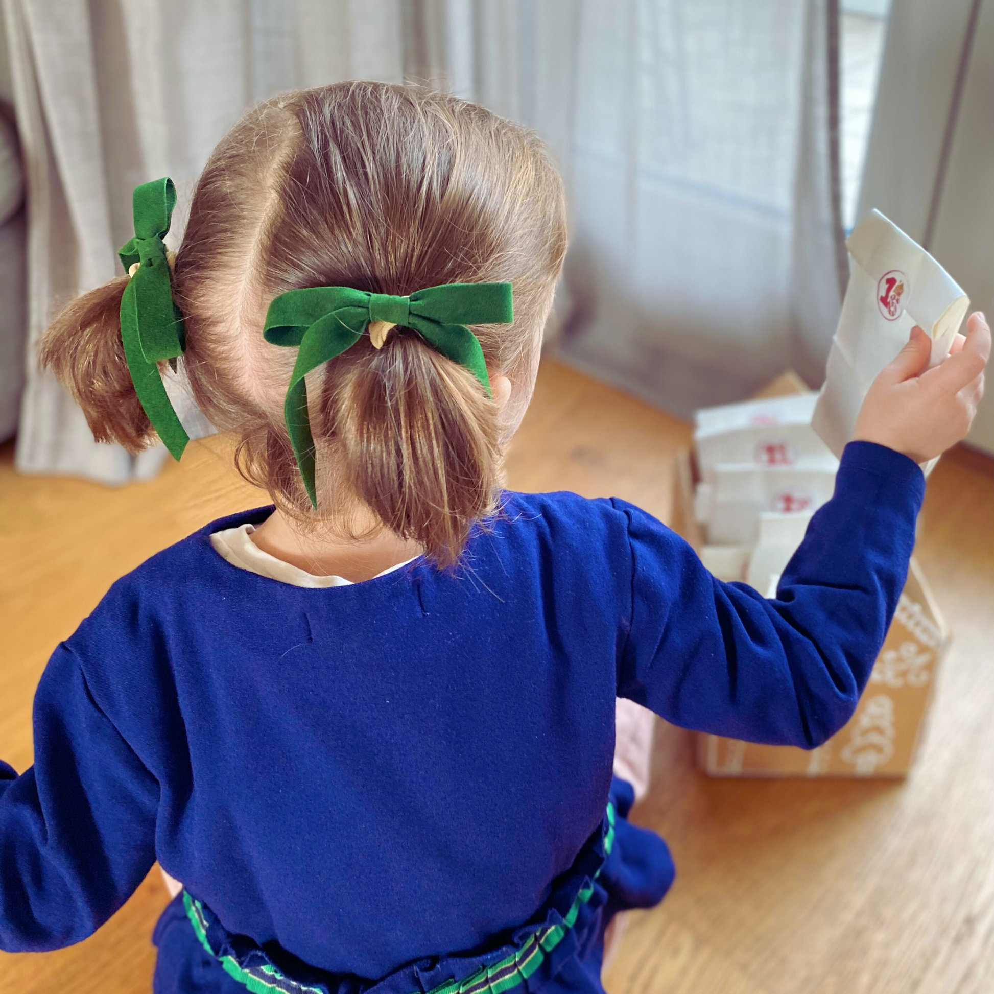 Fiocchi di velluto verde del set Velvet Holly usati come decorazioni per le codine di una bambina, perfetti per le feste natalizie. LAPEPIA.