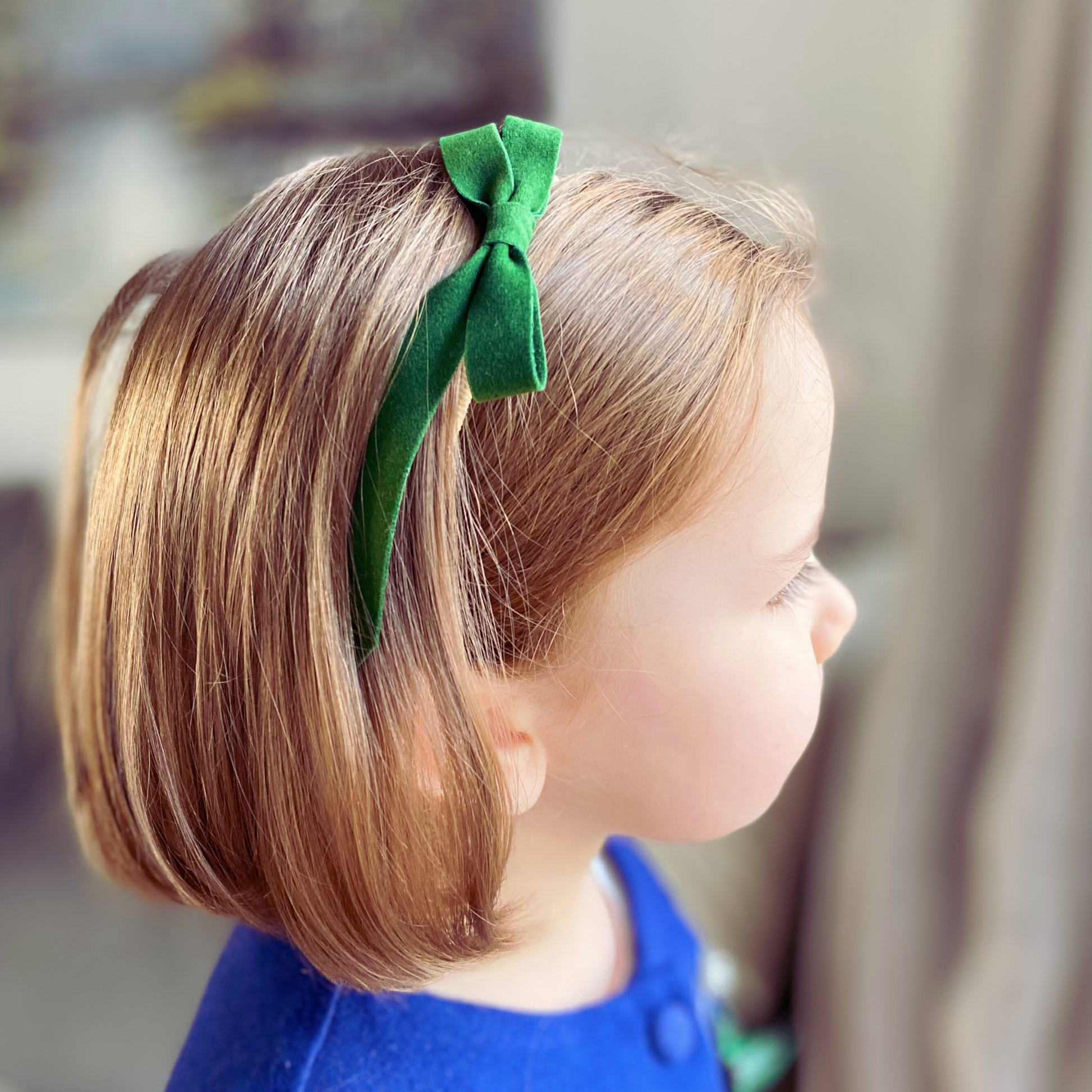 Fiocco di velluto verde del set Velvet Holly indossato come fascetta su una bambina, ideale per completare un look natalizio. LAPEPIA.